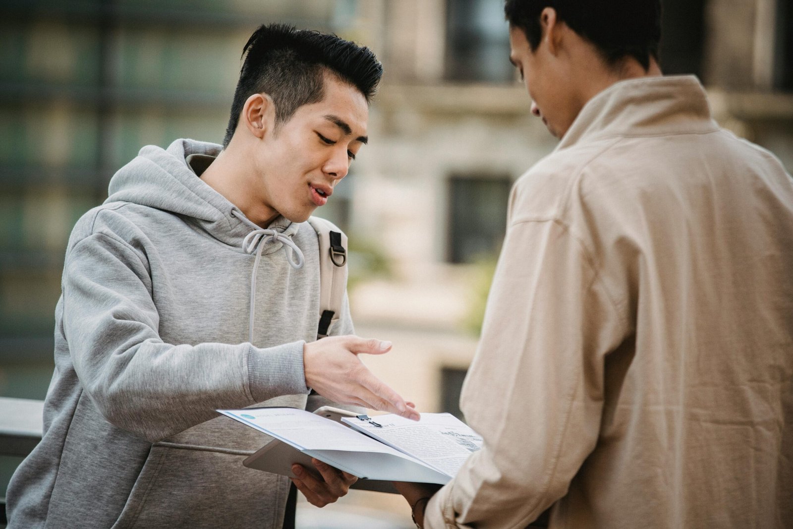 Concentrated multiracial friends talking about exam and discussing information about subjects on blurred background of street